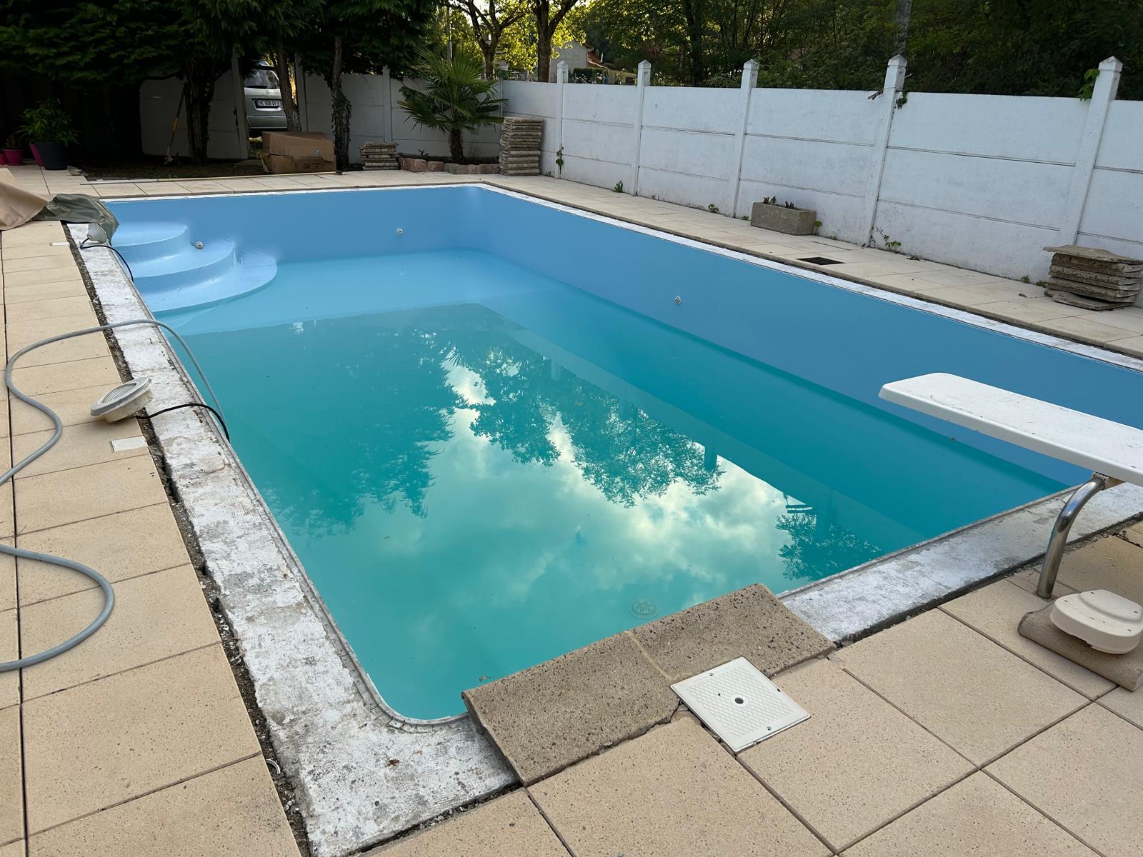 Piscine rénovée bleu ciel avec plongeoir